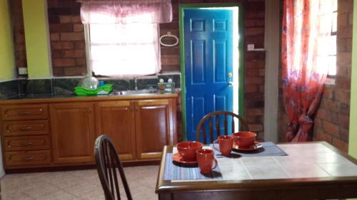 a kitchen with a table and a blue door at Seawind Cottage Authentic St.Lucian Accommodation near Plantation Beach in Gros Islet