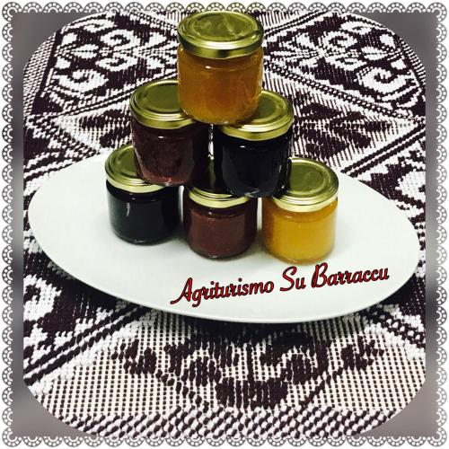 a plate with four jars of jam on a table at Agriturismo Su Barraccu in Loceri