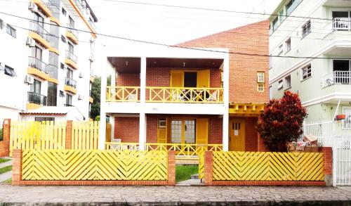 a house with a yellow fence in front of it at Apart Hotel Vila Mar in Florianópolis