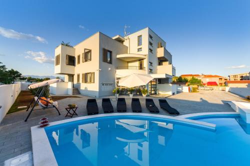 a villa with a swimming pool in front of a building at Apartments Menalo in Zaton