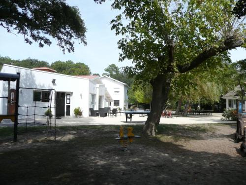 a picnic table under a tree next to a building at Cap Océan in Seignosse