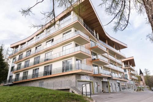 an apartment building with balconies on a street at Grand Apartments Hrebienok in Smokovce