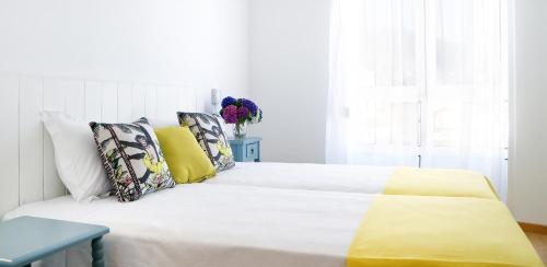 a white bedroom with a white bed with yellow sheets and pillows at Duerming Sea View Viveiro in Viveiro