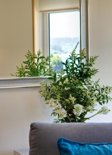 a vase of flowers sitting on a couch in front of a window at Duerming Sea View Viveiro in Viveiro