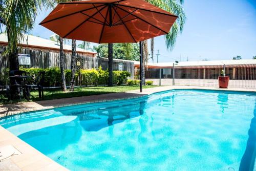 a swimming pool with an umbrella and a swimming pool at Clermont Country Motor Inn in Clermont