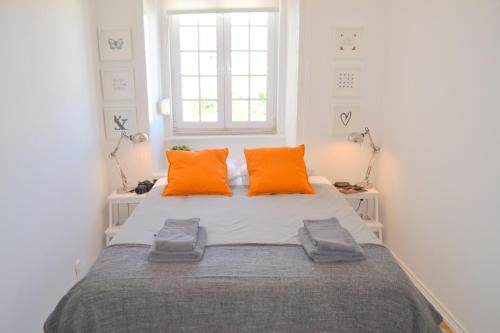ein Schlafzimmer mit einem großen Bett mit orangefarbenen Kissen in der Unterkunft TP MONTE 20, Lisbon Apartment in Lissabon