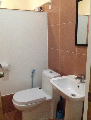a bathroom with a white toilet and a sink at Mangoes Place in Moalboal