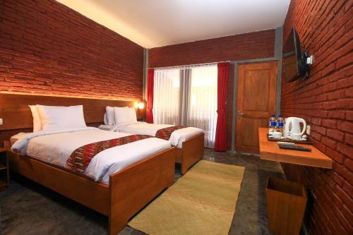 a bedroom with two beds and a brick wall at Wahid Borobudur in Borobudur