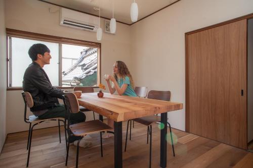 un hombre y una mujer sentados en una mesa en una habitación en Ninja TABI-NE, en Kanazawa