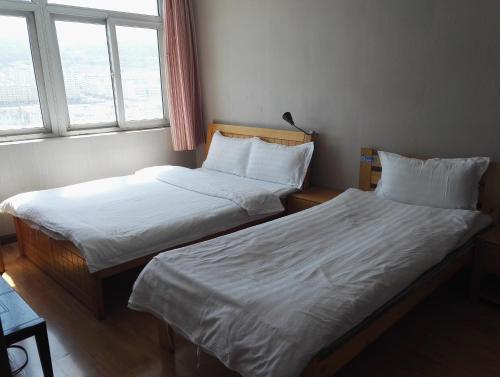 two beds in a room with two windows at LETE Hostel in Xining