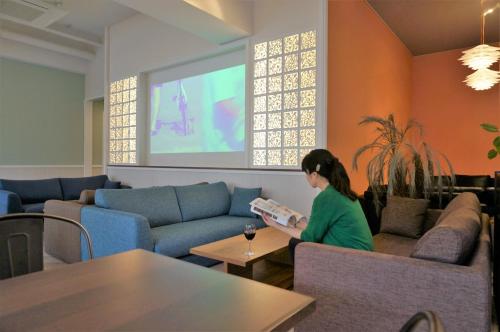 那覇市にあるAbest Cube Naha Kokusai Street-Cabin Type Hotel All Room With Keyの居間で本を読む女