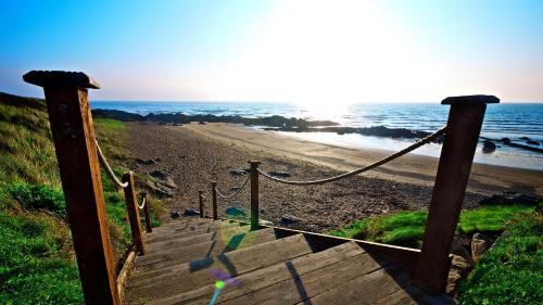 a wooden staircase leading to a beach with the ocean at Shoreline Hotel in Donabate