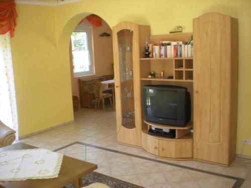 a living room with a tv and a book shelf at Kentaur Apartmanház in Siófok