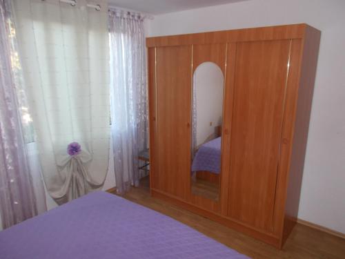 a bedroom with a wooden cabinet with a mirror at Apartments Makaus in Rab