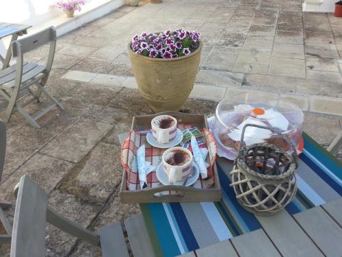 einen Tisch mit einer Kanne Blumen und Tassen Kaffee in der Unterkunft Mercanti in Manduria