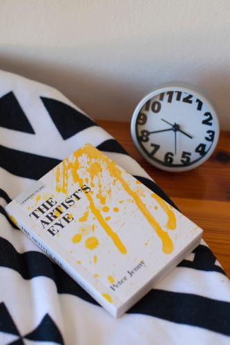 a book sitting on a bed next to a clock at Kamiros Apartment in Kalavárda