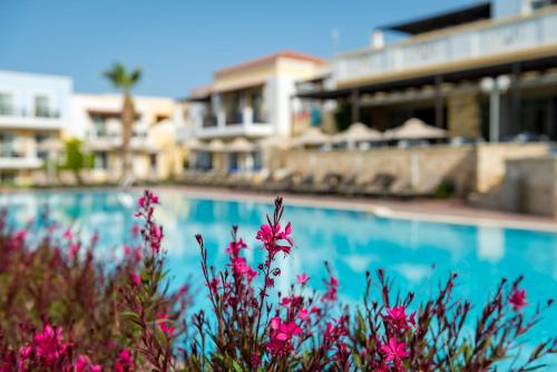 a pool with pink flowers in front of a building at Aegean Houses in Kos