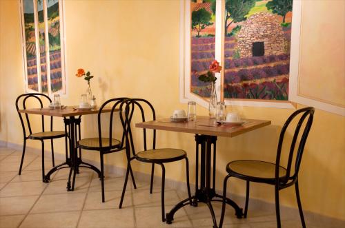 two tables and chairs in a room with a painting at Le Signoret in Sault-de-Vaucluse