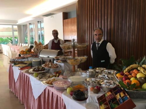 zwei Männer, die vor einem Tisch stehen in der Unterkunft Hotel Beau Rivage Pineta in Lido di Jesolo