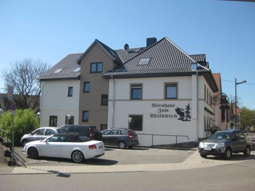 a building with cars parked in a parking lot at Wirtshaus zum Wilddieb in Bad Rappenau