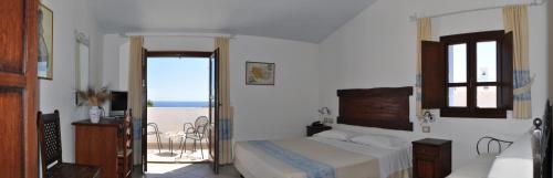 a bedroom with a bed and a balcony with the ocean at Hotel Resort Nuraghe Arvu in Cala Gonone