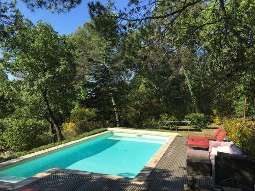 a swimming pool with a deck and chairs and trees at Villa de Carbonelle in Pierrevert