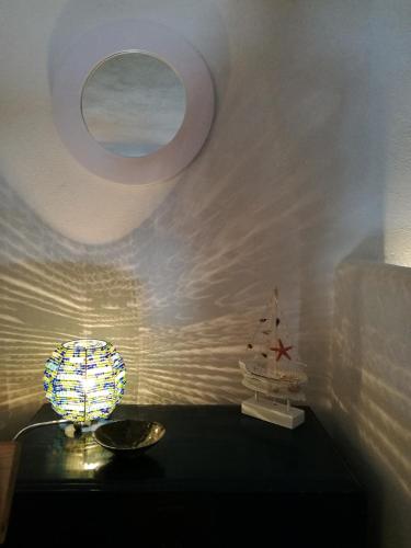 a room with a table with a lamp and a mirror at La Casa di Via Lungomare in Santa Marina Salina
