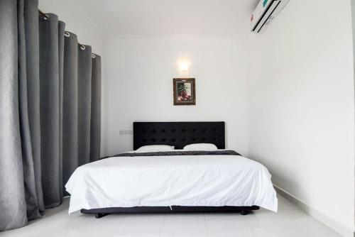 a bedroom with a bed with a black headboard and curtains at Langkawi Primrose Seaview in Tanjung Rhu 