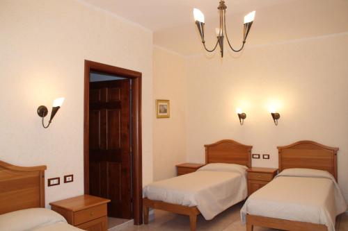 a room with three beds and a chandelier at Hotel Ristorante L'Avvenire in Gizzeria