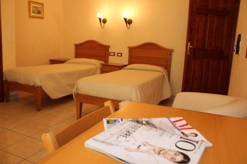 a hotel room with two beds and a magazine on a table at Hotel Ristorante L'Avvenire in Gizzeria