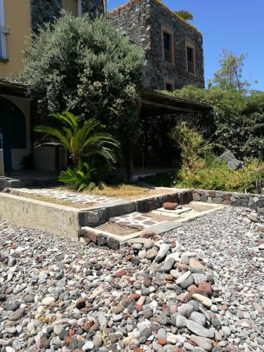 a rocky yard with a house in the background at La Casa di Via Lungomare in Santa Marina Salina