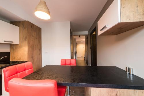 een keuken met een zwart aanrecht en rode stoelen bij La Clé des Champs in Annecy