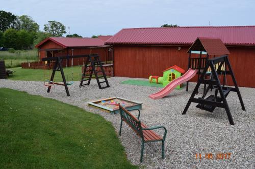 um parque infantil com dois baloiços e um conjunto de jogos em Aga domki letniskowe em Rewal