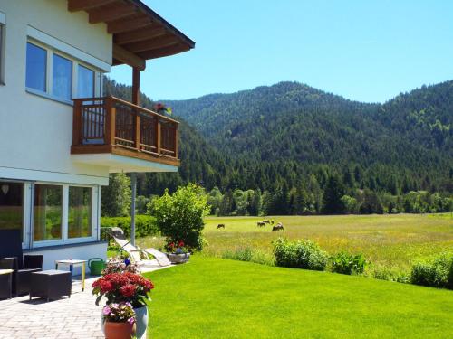 a house with a balcony and a field of grass at Appartements Erhol dich gut in Leutasch