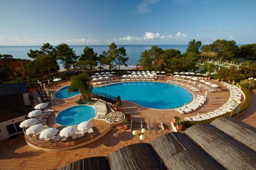 einen Blick über einen Pool mit Sonnenschirmen und Stühlen in der Unterkunft PortoBay Falesia in Albufeira