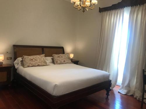 a bedroom with a bed with white sheets and a chandelier at Casa Palacio VillaZambra in Ronda