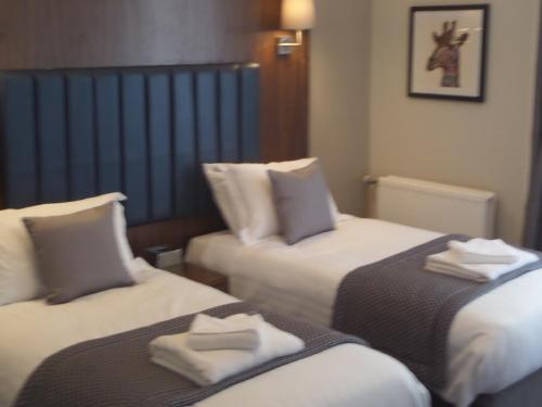two beds in a hotel room with towels on them at The Croft Hotel in Darlington