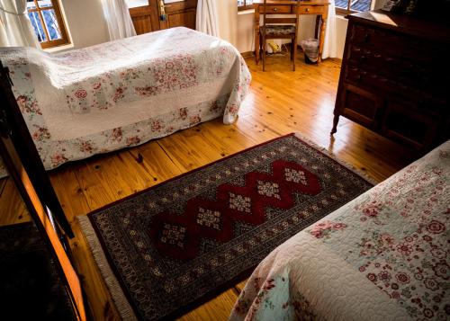 a room with two beds and a rug on a wooden floor at Mon-Ae Guesthouse in Klerksdorp