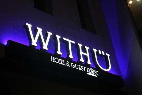 a lit up sign for a hotel and guest house at With U Hotel & Guesthouse in Sokcho