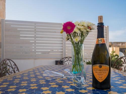 a bottle of wine and a vase of flowers on a table at Chapel 5 Boutique Suites B&B in Naxxar