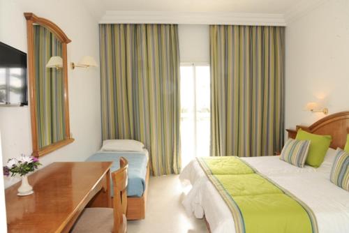 een hotelkamer met 2 bedden, een tafel en een bureau bij Yadis Hammamet in Hammamet