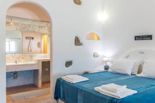 a bedroom with a blue bed with a sink and a mirror at Eleni's Village Suites in Klouvas