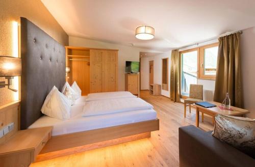 a hotel room with a large bed and a couch at Hotel Alpina in Rauris
