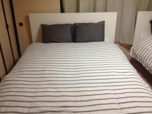 a bed with a black and white striped comforter at Share House on the Hill in Yokohama