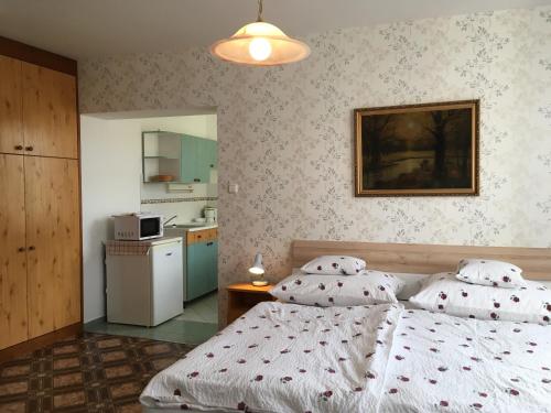 a bedroom with two twin beds and a kitchen at Gitta Apartman in Bük