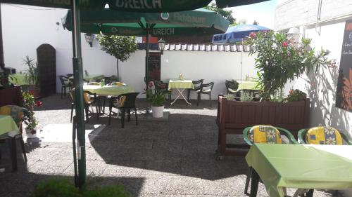an outdoor patio with tables and chairs and an umbrella at Gasthof Schillereck in Lorsch