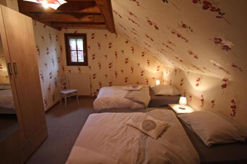 una habitación con 3 camas y una pared con flores en Les jumeaux en Granges-sur-Vologne