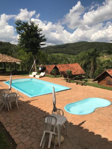 a large swimming pool with chairs and a table at Pousada Gota de Minas in Santo Antônio do Leite