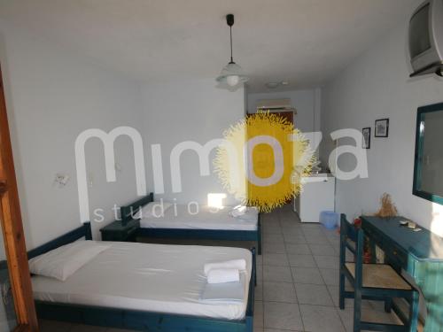 a room with two beds and a yellow sign on the wall at Mimoza Studios in Skiathos Town