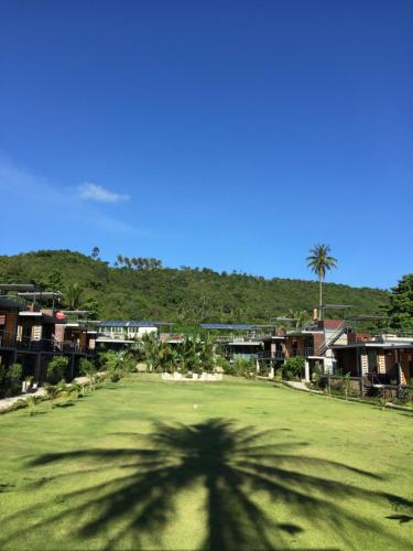 a shadow of a palm tree on a green field at Baan Boom Boxes Eco Friendly Resort in Mae Nam